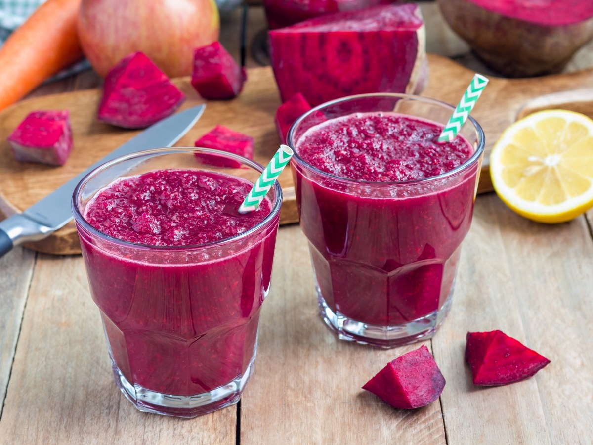 Zwei Gläser vom Rote-Bete-Apfel-Smoothie auf einem Holztisch.