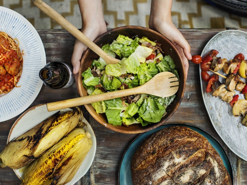 Salate zum Grillen: Grillbuffet in der Draufsicht, darauf u.a.a Mais, Spieße und eine Salatschüssel.