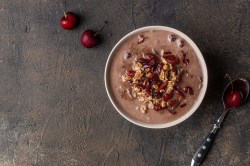 Eine Schüssel Schwarzwälder-Kirsch-Porridge mit Kirschen getoppt, Draufsicht.