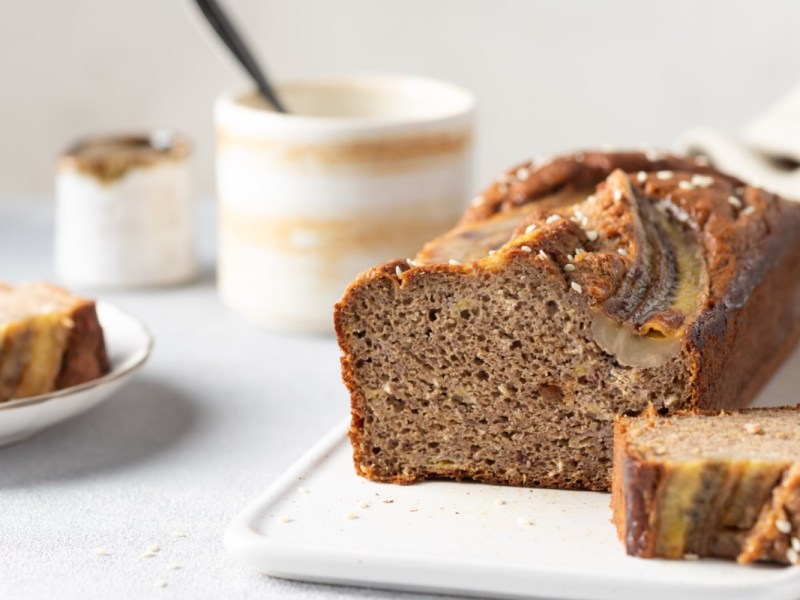 Ein aufgeschnittenes Tahini-Bananenbrot auf einem Brett.