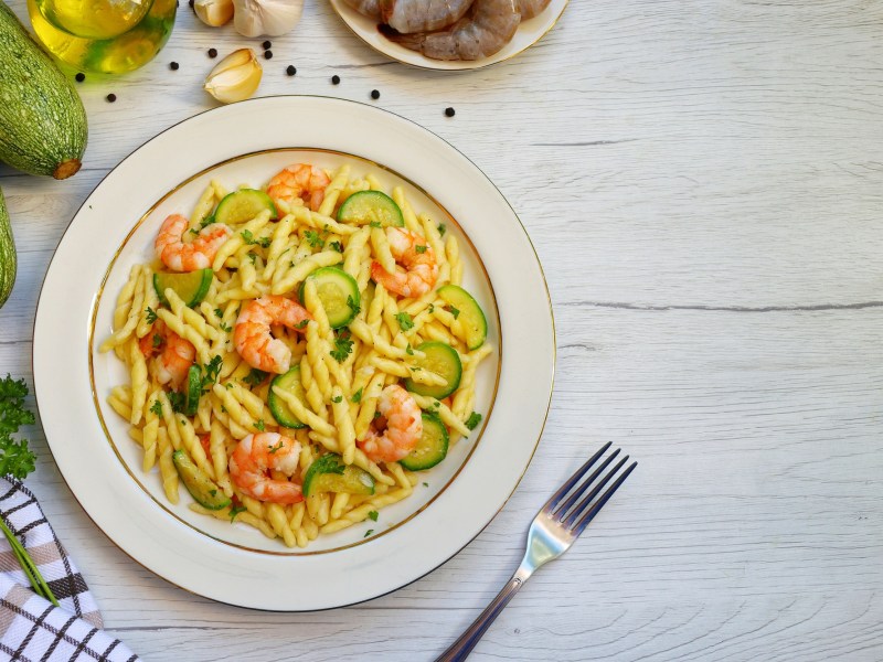 Trofie mit Zucchini und Garnelen auf einem Teller.