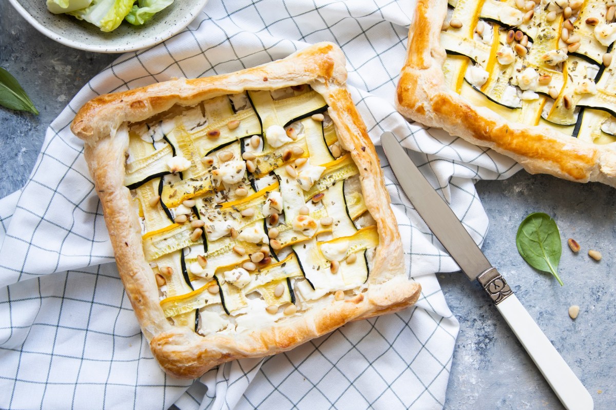 Zwei Zucchini-Blätterteig-Tartes auf kariertem Tischtuch