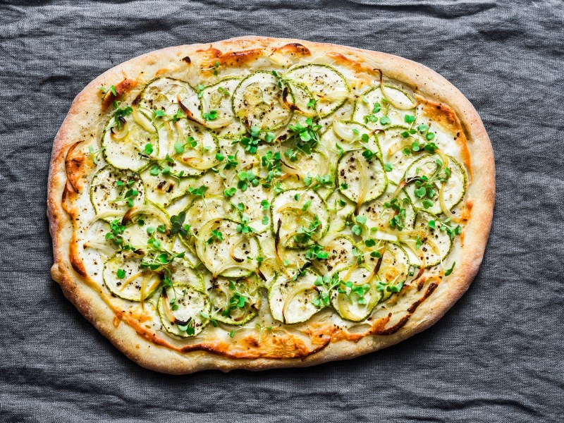 Eine Zucchini-Pizza auf einer Tischdecke.