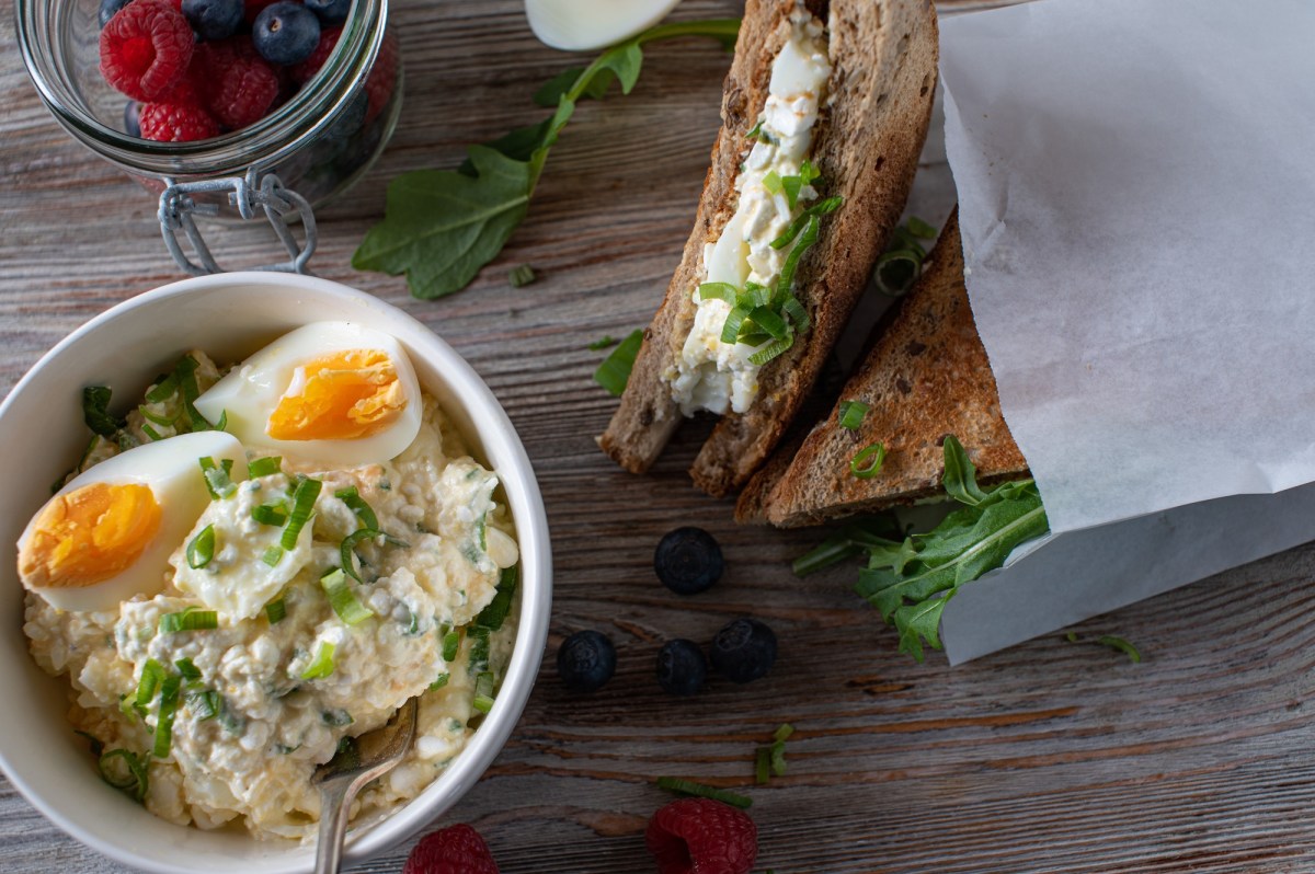 Eine Schale Eiersalat mit Hüttenkäse und belegte Brote