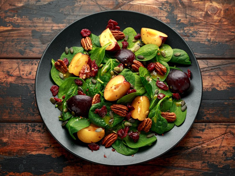 Schüssel mit Salat mit karamellisierten Pflaumen und Pekannüssen