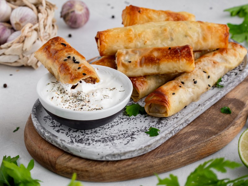 Feta-Röllchen auf einem Tablett mit Dip.