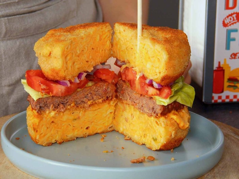 Ein aufgeschnittener Mac’n’Cheese-Burger auf einem Teller.