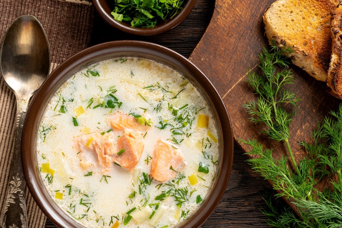 Eine Schüssel schwedische Sommersuppe in der Draufsicht. Daneben liegen frische Zutaten.