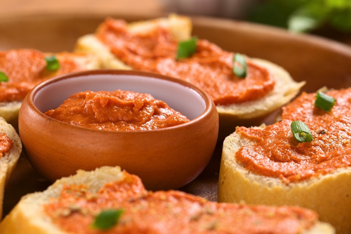 Eine Schale Tomatenbutter, drumherum Baguettescheiben mit der Butter bestrichen.