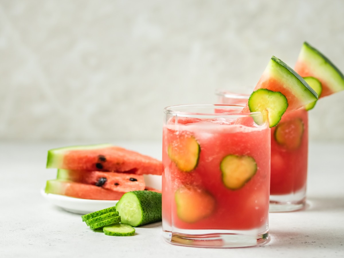 Zwei Gläser Wassermelonen-Mojito, geschnittene Melone daneben