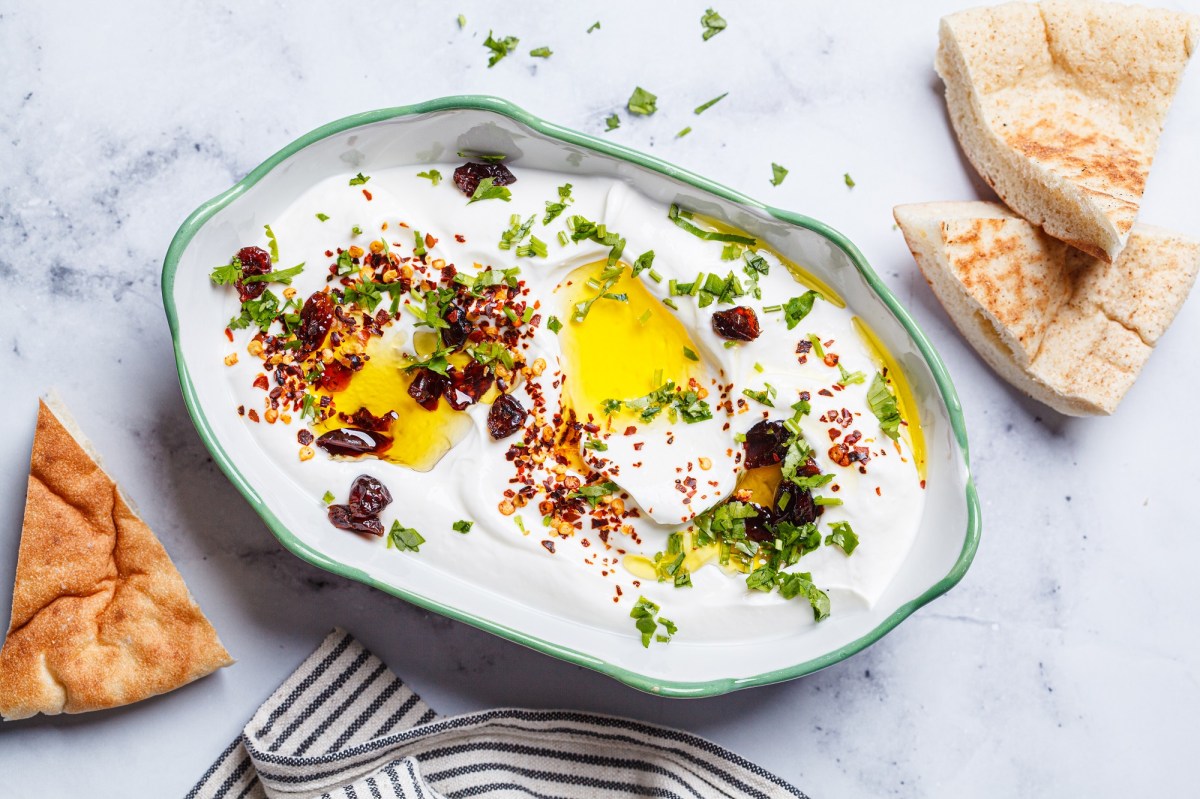 Whipped Feta-Dip, garniert mit Öl, Petersilie und Chili, in einer Schüssel mit grünem Rand.