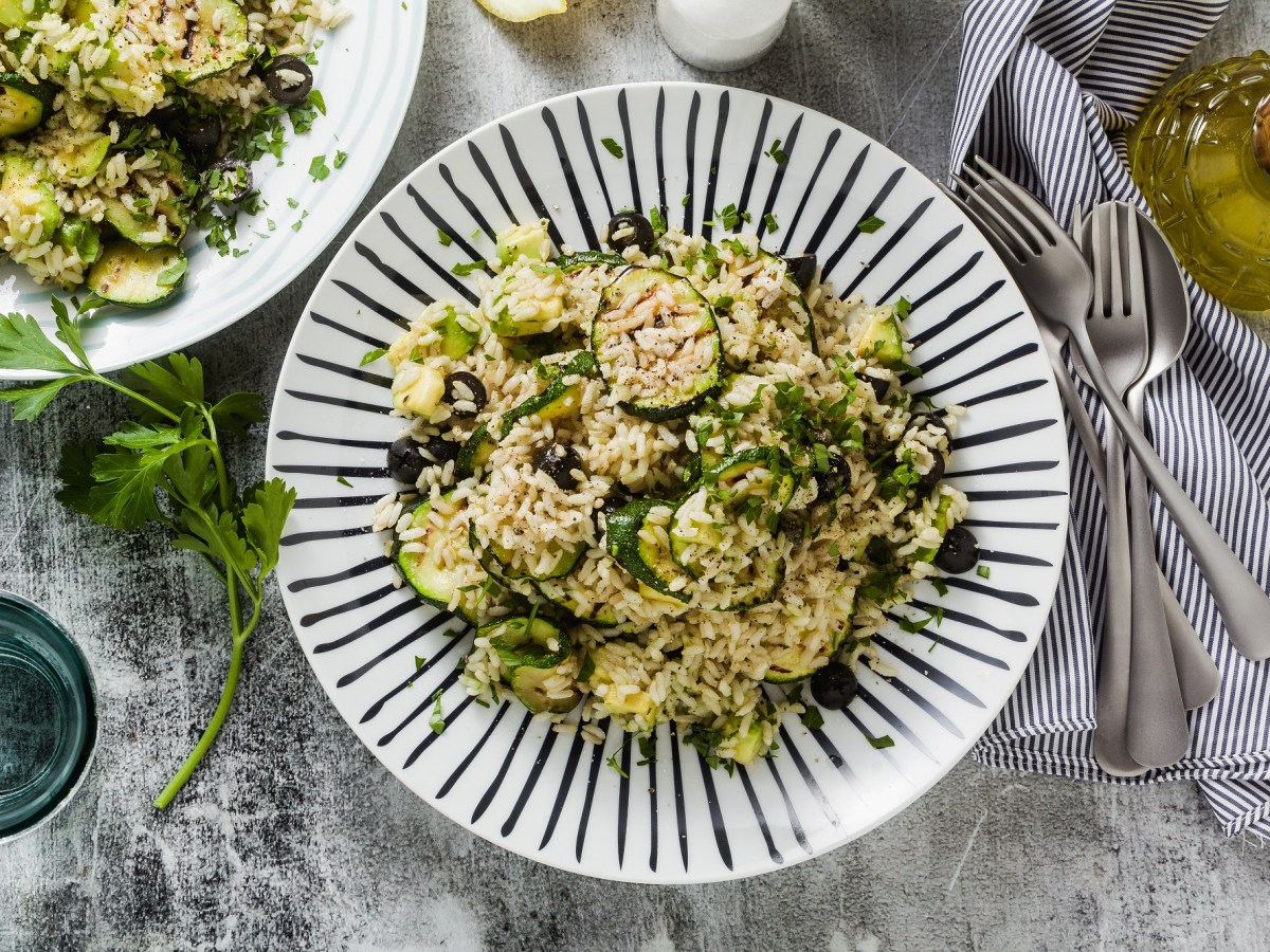 Zucchini-Reissalat auf einem blau-weiß gestreiften Teller.