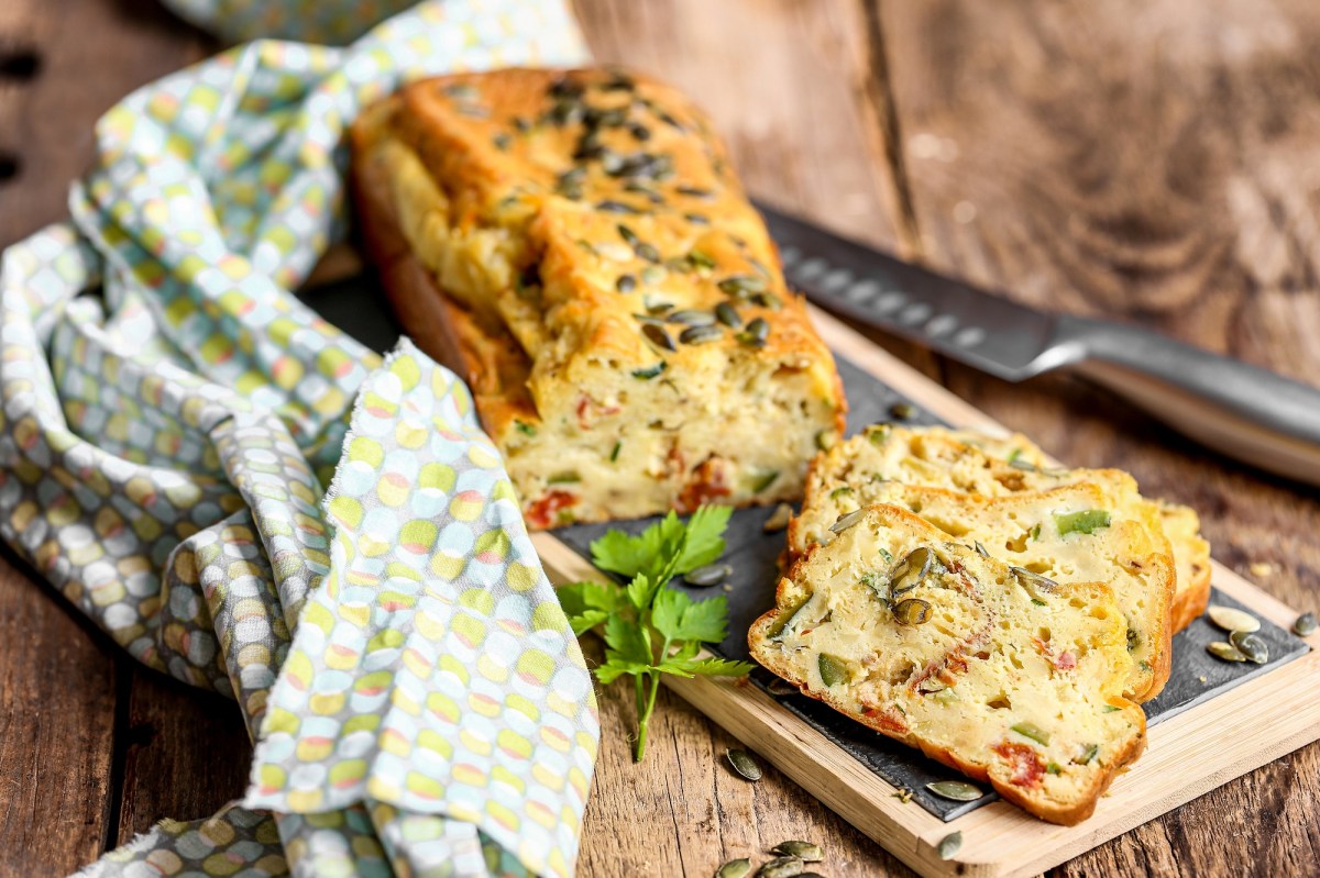 Zucchinibrot mit getrockneten Tomaten auf einem Holzbrett.