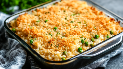 Alfredo-Reisauflauf mit Hähnchen, Erbsen und Semmelbröseln in quadratischer Auflaufform aus Glas.