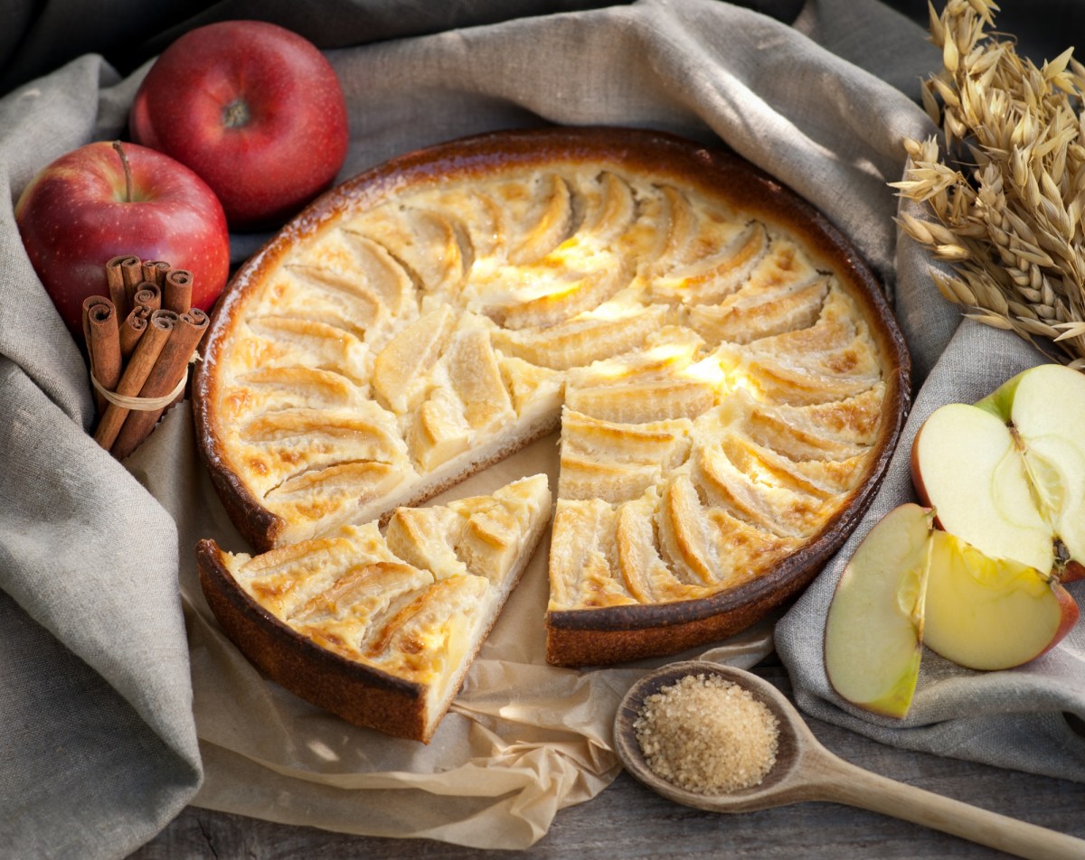 Apfel-Marzipan-Tarte auf einem Küchentuch, Äpfel daneben