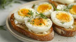 2 Ei-Toasts mit Joghurt-Frischkäse-Aufstrich auf einem Teller, mit Kräutern bestreut.