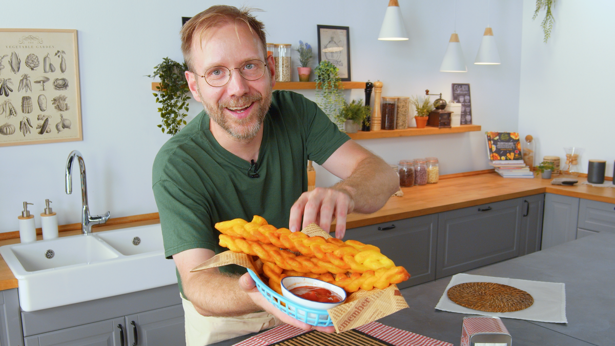 Koch präsentiert einen Teller mit geflochtenen Pommes