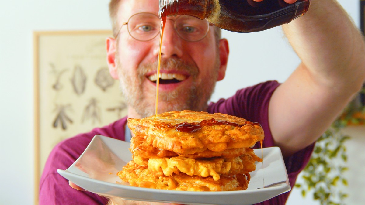 Ein Koch träufelt Sirup über einen Teller mit Kohl-Hackfleisch-Pancakes.