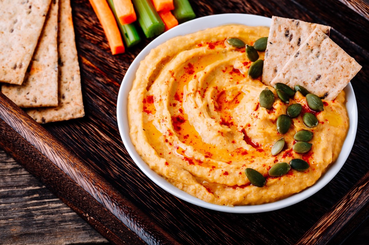 Schale mit Kürbis-Frischkäse-Dip auf Tablett, Cracker und Gemüsesticks