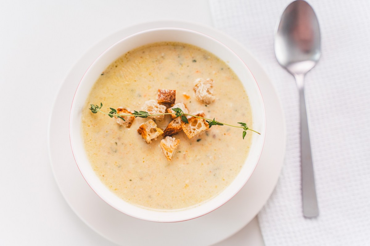 Schüssel mit Parmesan-Suppe und Löffel