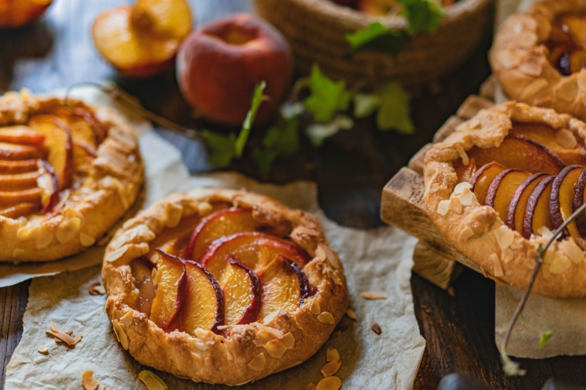 Mehrere Pfirsich-Galettes. Im Hintergrund liegen frische Pfirsiche.