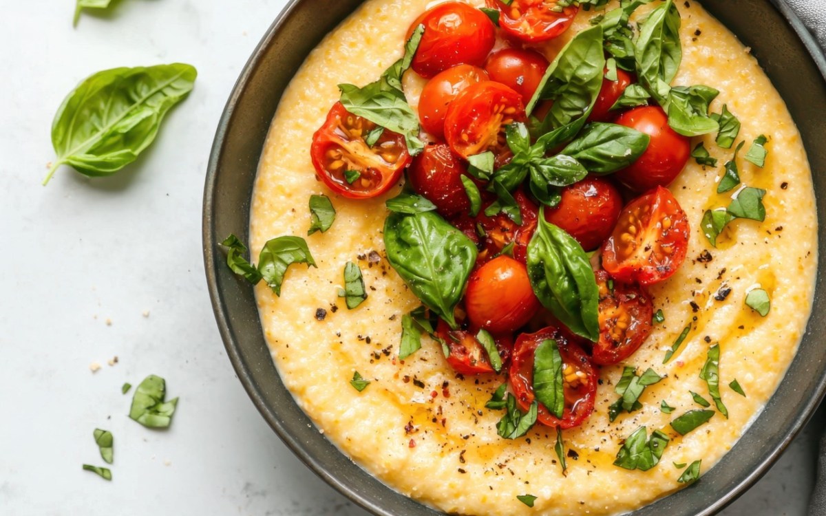 Eine Schüssel mit Polenta mit Tomaten und Basilikum in der Draufsicht.