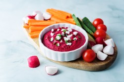 Schälchen mit Rote-Bete-Feta-Dip und Gemüsesticks daneben.