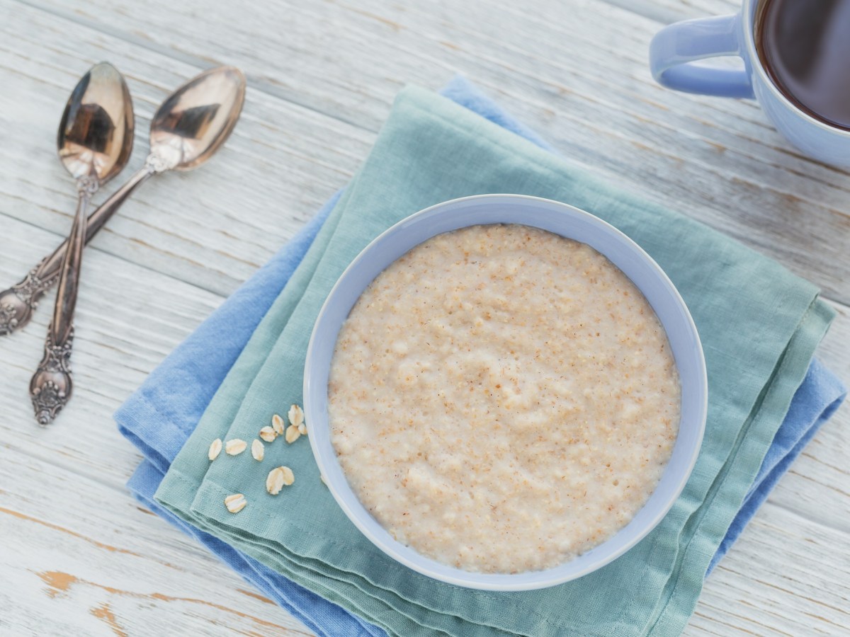 Schottischer Porridge in einer hellblauen SchÃ¼ssel, daneben ligeen zwei LÃ¶ffel.