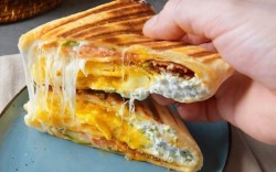 Ein Frühstücks-Sandwich-Wrap wird aufgeschnitten in einer Hand gehalten.