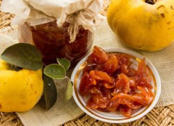 Ein Glas Quitten-Chutney, daneben ein Teller mit dem Chutney und zwei frische Quitten.