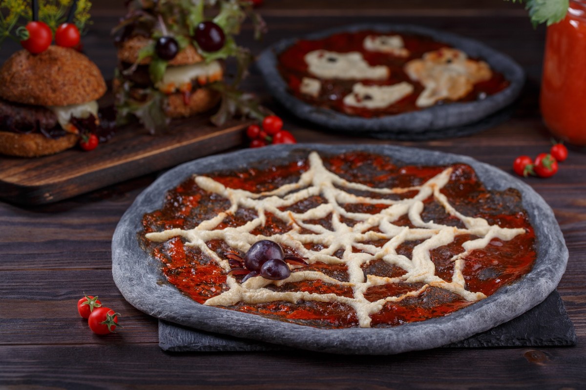 Eine schwarze Halloween-Pizza mit Spinnennetz.