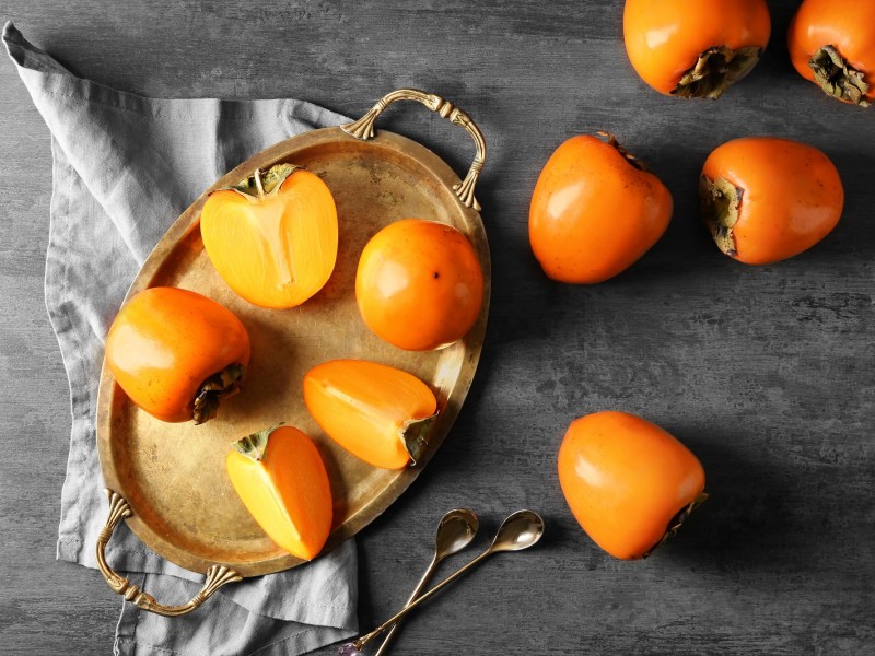 Unterschied Kaki, Sharonfrucht, Persimone: Einige angeschnittene Früchte liegen auf einem Tablett.