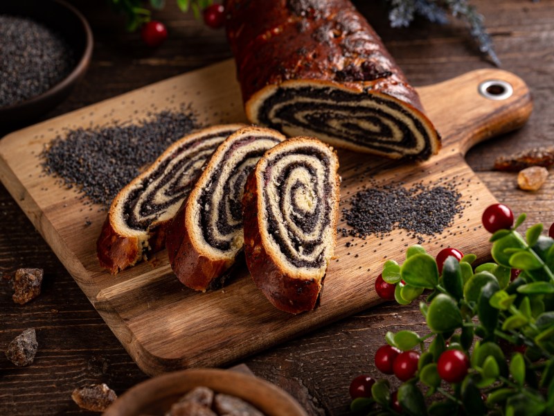 Beigli - ungarischer Mohnstrudel angeschnitten auf einem Holzbrett.