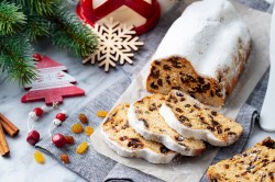 Christstollen-Rezept: ein angeschnittener Stollen mit Puderzucker bestreut, drumherum etwas Weihnachtsdeko.