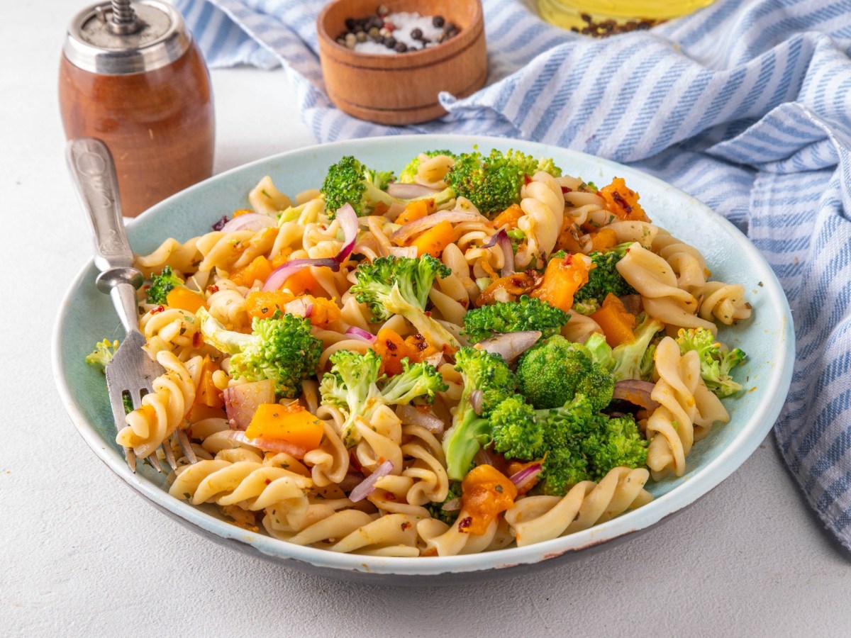 Herbstlicher Nudelsalat mit Brokkoli und Kürbis auf einem tiefen Teller.