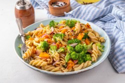 Herbstlicher Nudelsalat mit Brokkoli und Kürbis auf einem tiefen Teller.