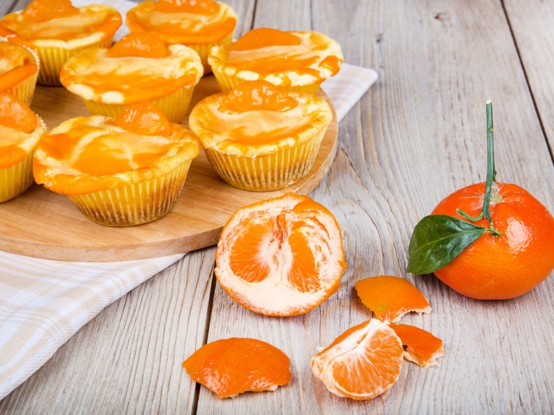 KÃ¤sekuchen-Muffins aus der HeiÃŸluftfritteuse, davor eine frische Mandarine.