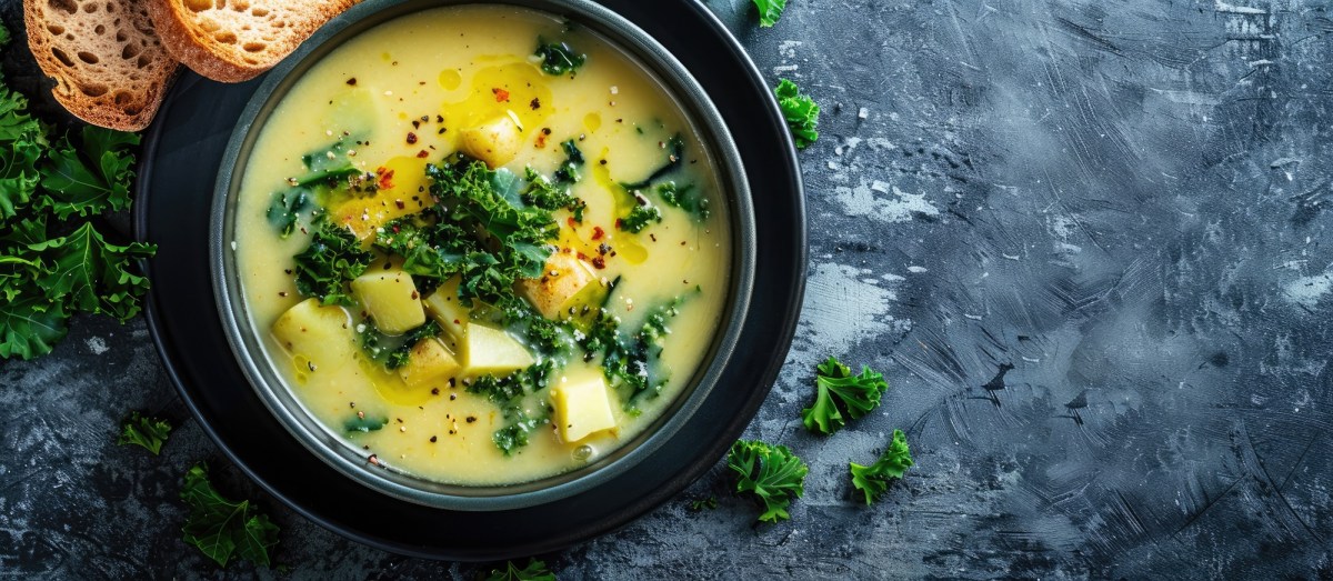 Schale mit Kartoffelsuppe mit GrÃ¼nkohl, Brot daneben.