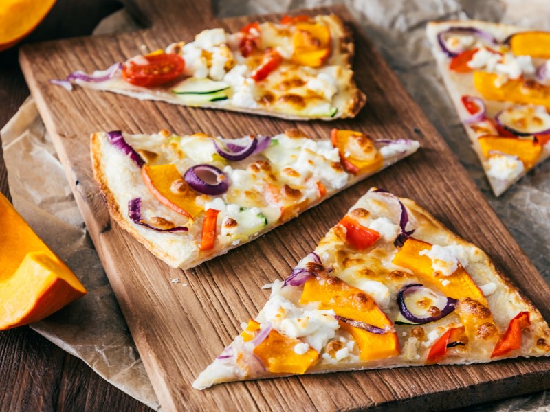 Brett mit drei Stücken Kürbis-Flammkuchen mit Feta