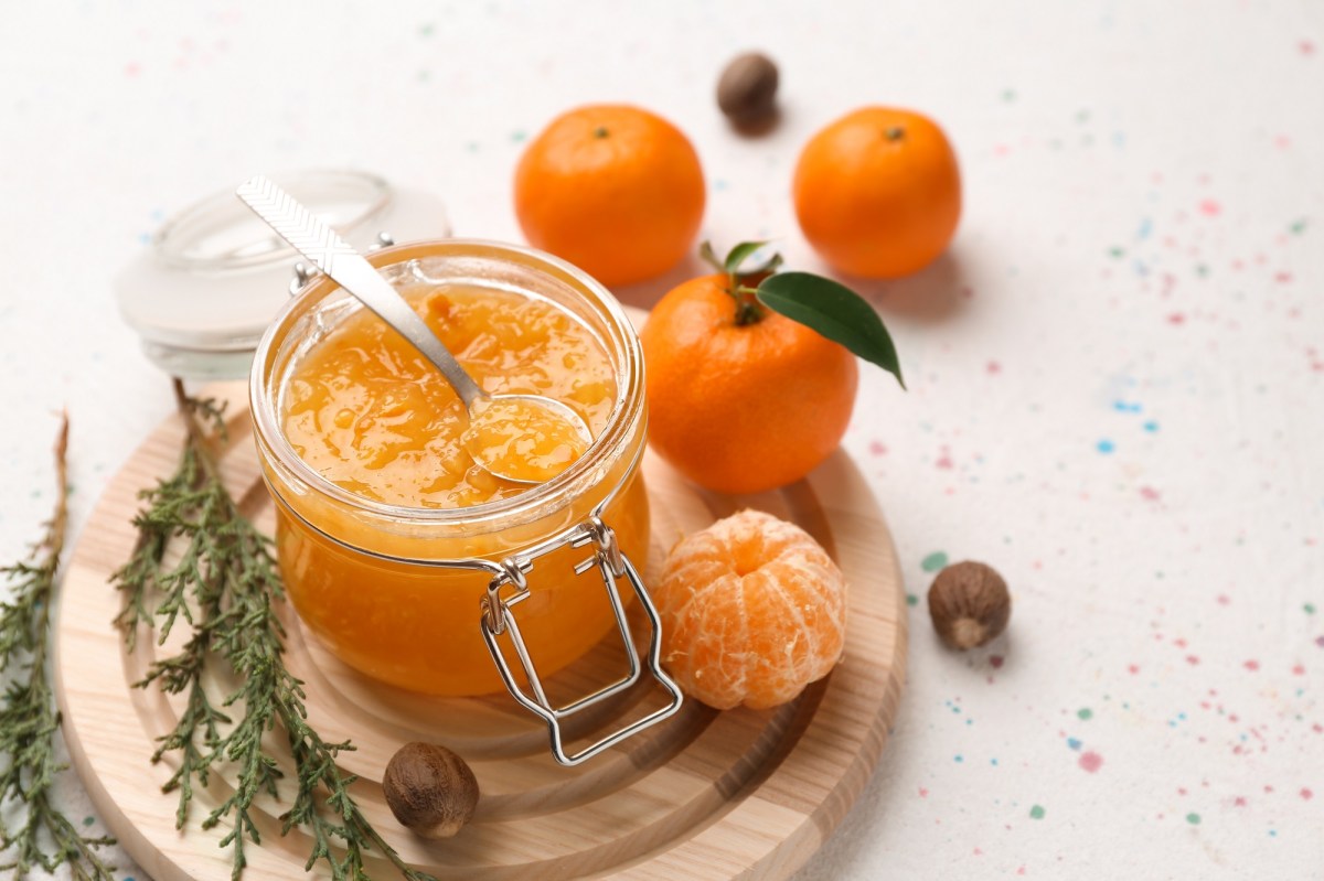 Glas Mandarinenmarmelade mit Mandarinen daneben