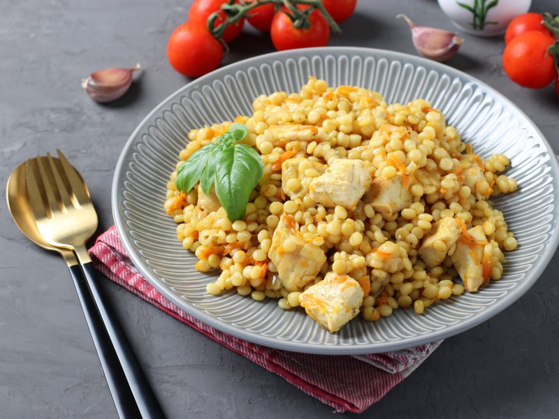 Perlcouscous mit Hähnchen auf einem Teller.