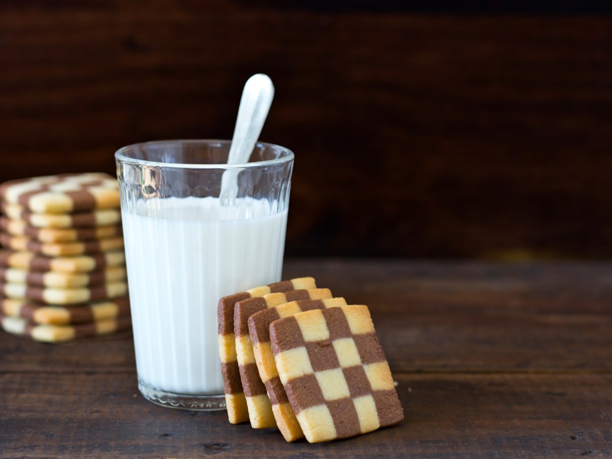 Schwarz-WeiÃŸ-GebÃ¤ck, das an einem Glas Milch lehnt.