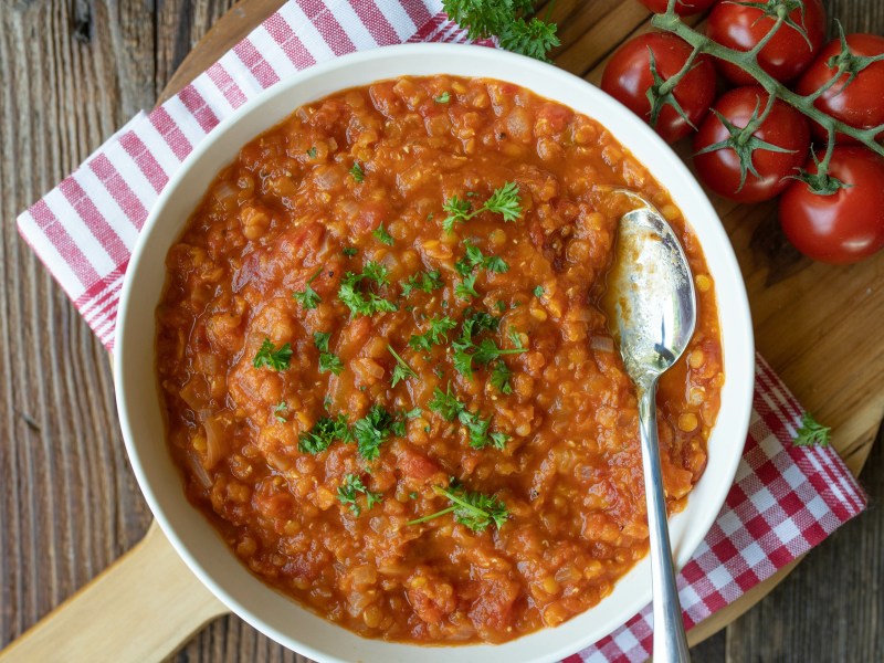 Eine SchÃ¼ssel Tomatensuppe mit Linsen.