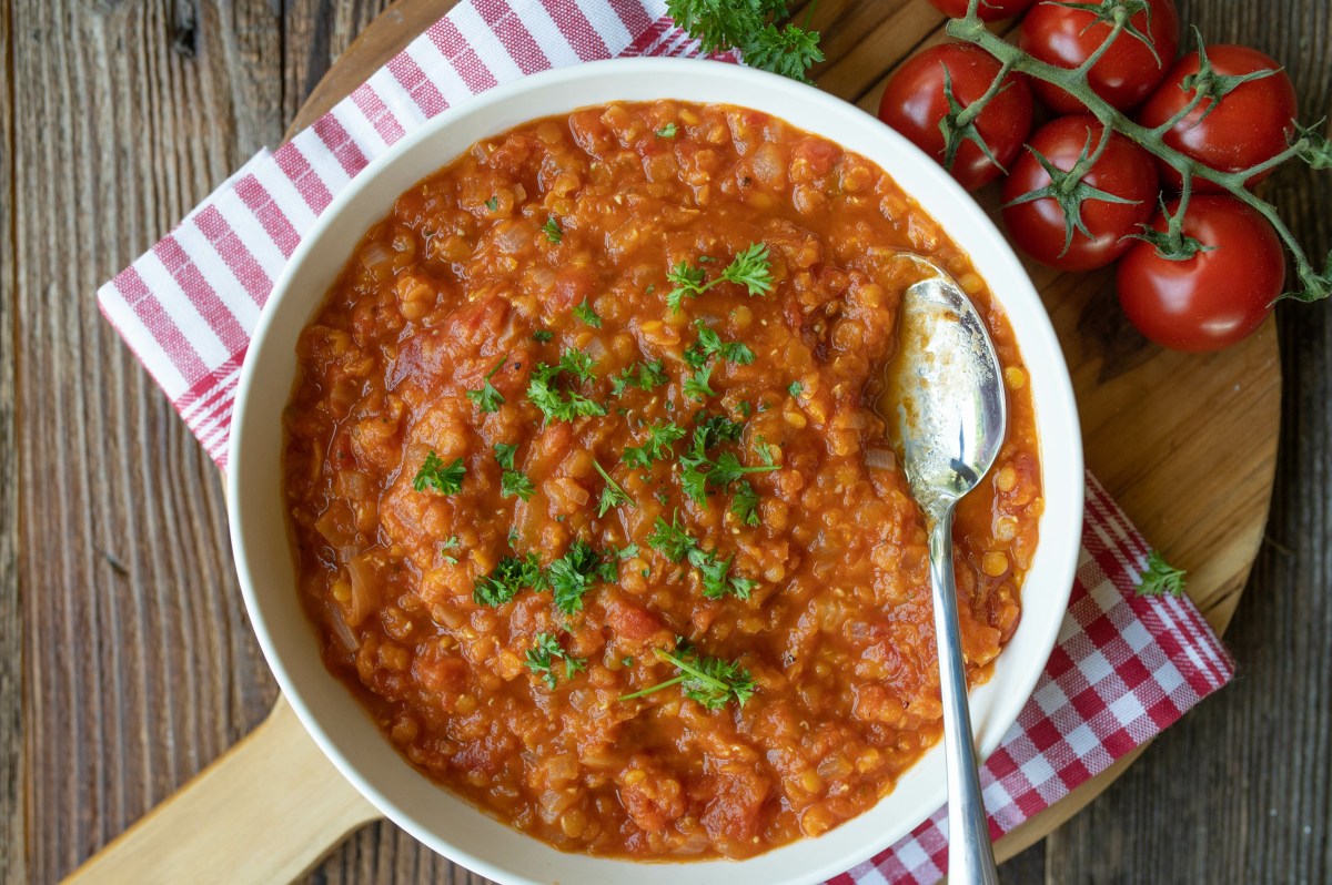 Eine SchÃ¼ssel Tomatensuppe mit Linsen.