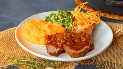 Zwiebelrostbraten mit Kürbispüree und Röstzwiebeln auf einem Teller.