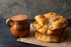 Buñuelos: mexikanische Weihnachtskrapfen neben einer Tasse mexikanischer heißer Schokolade.