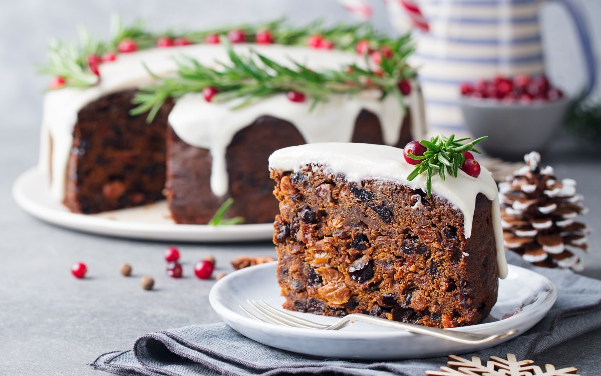 Ein StÃ¼ck Englischer Weihnachtskuchen. Im Hintergrund ist der Rest des Kuchens zu sehen.