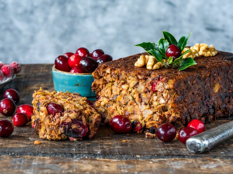 Ein angeschnittener Nussbraten, drumherum Zutaten wie frische Cranberrys.