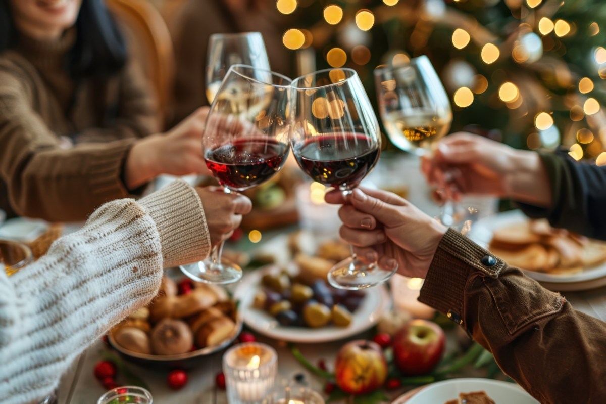 GemÃ¼tliche Runde stÃ¶ÃŸt beim Essen mit Wein an.