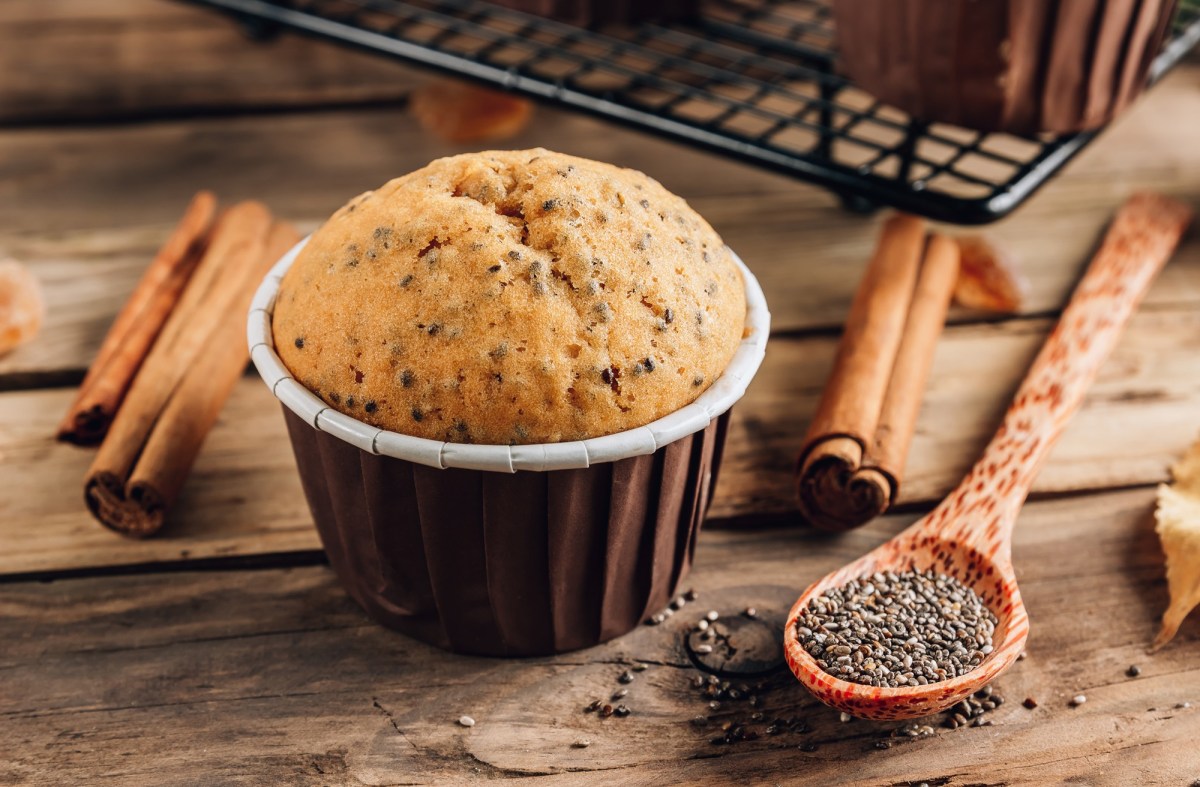 Ein Zimtmuffin. Daneben liegen ein LÃ¶ffel Chiasamen und einige Zimtstangen.